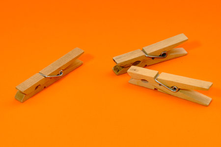 Set of wooden clothespins that appear one by one on an orange background.の写真素材