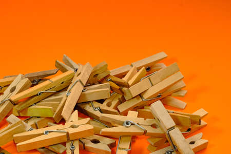 Set of wooden clothespins that appear one by one on an orange background.の写真素材