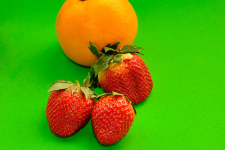 Set of oranges and strawberries that appear, on a green background.の写真素材