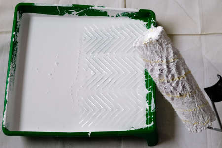 White paint roller collecting paint in a paint container.の写真素材