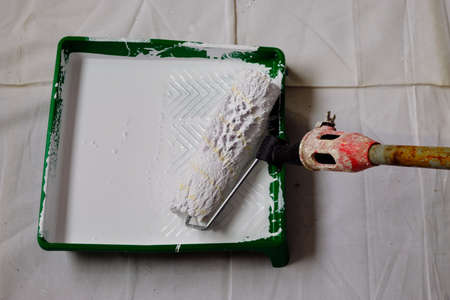 White paint roller collecting paint in a paint container.の写真素材