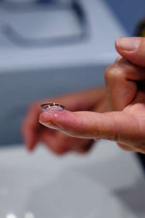 A woman's hands with a contact lens. Vision Correction and Health Care. Contact Lenses.