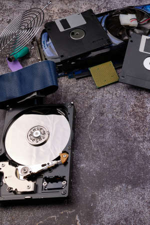 Composition of various computer components on a dark background similar to cement, different computer components such as hard drives, disk drives, graphic controller, micro chips, fans and heat sinks.の写真素材