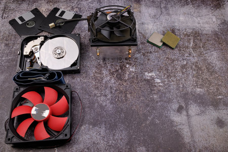 Composition of various computer components on a dark background similar to cement, different computer components such as hard drives, disk drives, graphic controller, micro chips, fans and heat sinks.の写真素材