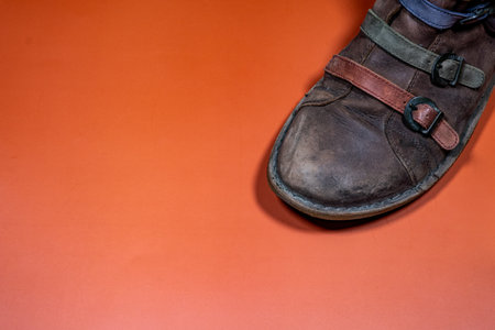 Worn-out Shoe Detail with Colorful Leather Strips on Brown Backgroundの写真素材