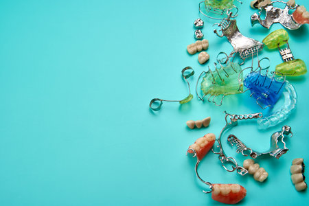 Different orthodontic appliances in many colors on top of a green table, with copy space.