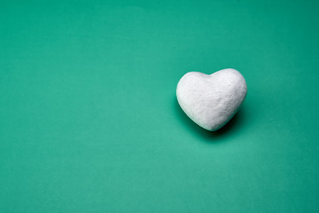 White heart representing the purity of love on a green background.の写真素材