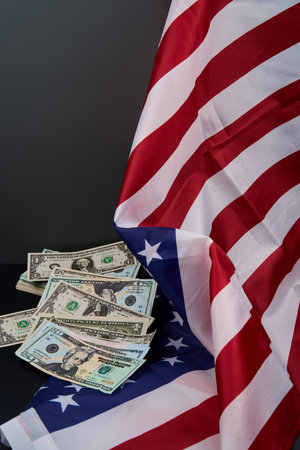 A stack of cash rests on an American flag, symbolizing wealth and patriotismの写真素材