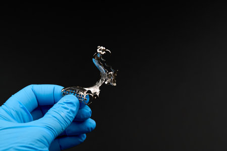 A person in blue gloves holds a piece of metal with an electric blue tintの写真素材