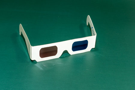 A pair of paper 3D glasses on green background