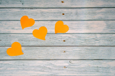 Four orange paper hearts on a bluish wooden tableの写真素材