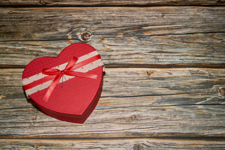 Red gift box with bow ribbon on wooden surfaceの写真素材