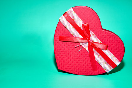 Red heart box with ribbon on a teal backgroundの写真素材