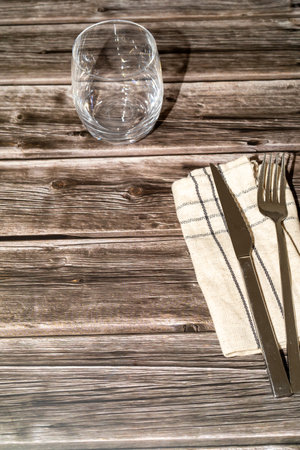 knife, fork and a transparent glass on top of a wooden tableの写真素材