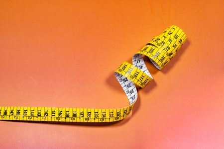 Tailor measuring tape in spiral rounds placed on orange surface