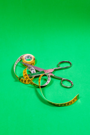 Tape measure and sharp tailors scissors, placed on the table.
