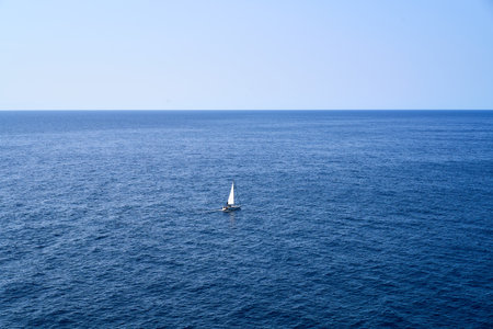 alone white sailboat rides in summer day at blue sea with horizon and copy space