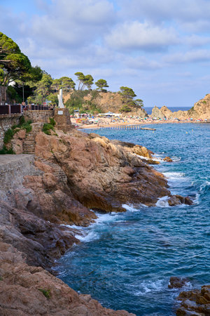 Sea hitting the rocks of the coast and the beach on a sunny day. Spain, Tossa del Mar.