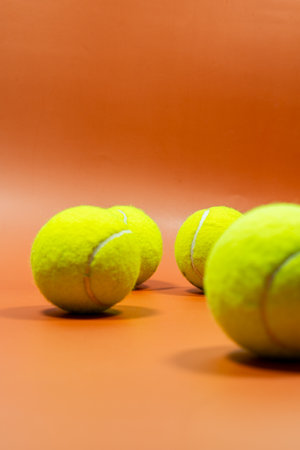 Close up view of a stack of bright yellow tennis balls on an orange surface.の写真素材