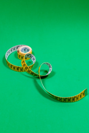Tailor measuring tape in spiral rounds placed on green surface