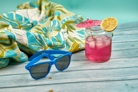 Refreshing drink, sunglasses and tropical towel, ready for the beach.の写真素材