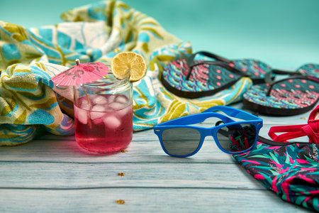 Refreshing drink, sunglasses, swimsuit, flip-flops and towel, ready for the beach.の写真素材