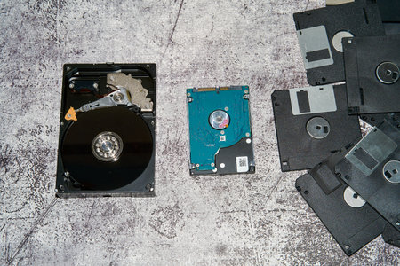 Hard drives and floppy disks on grayish surface.