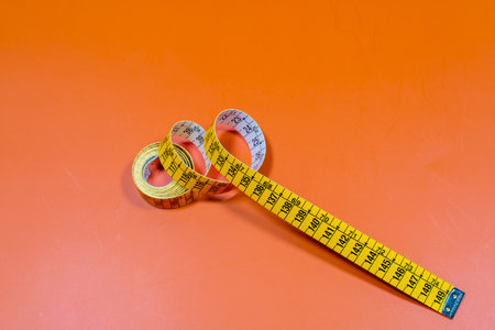 Tailor measuring tape in spiral rounds placed on orange surface
