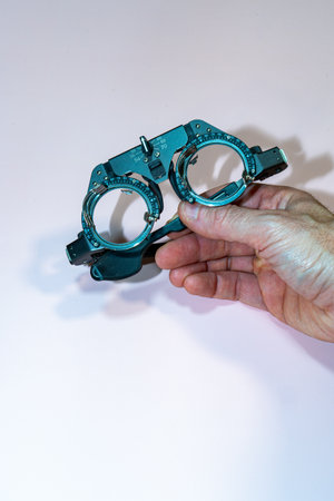 Hand holding a pair of test goggles on a pink table