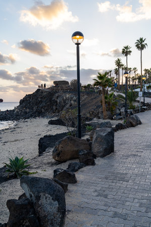 Evening stroll on the beachside promenade in Lanzarote with palm trees and ocean views.の写真素材