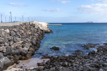 Stunning coastal view in Lanzarote featuring a rocky breakwater and the clear Atlantic ocean.