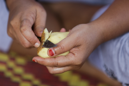 Woman prepare food, pill potato skin with knifeの写真素材