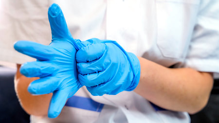 Doctor or nurse putting on blue nitrile surgical gloves, professional medical safety and hygiene for medical exames or protection against coronovirusの写真素材
