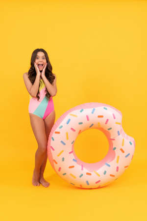 surprised beach child in swimming suit with doughnut inflatable ring, summer activity.の写真素材
