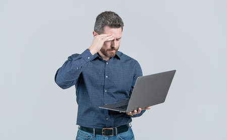 tired handsome mature man businessman with beard working online on laptop, office workerの写真素材