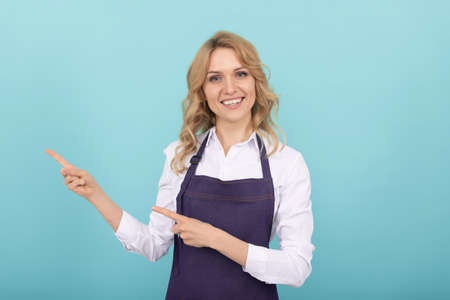 happy girl barista in cook apron pointing finger, advertisementの写真素材