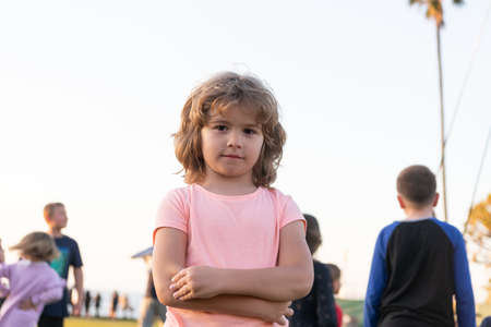 Serious boy child keep arms crossed summer outdoors, kid