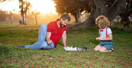 father and son play chess on grass in summer park, familyの写真素材