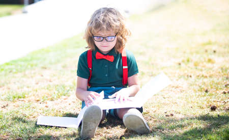 smart curious nerd in glasses reading book study with copybook outdoor, back to schoolの写真素材