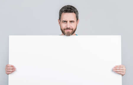 smiling mature bearded man behind blank white paper banner with copy space for offer, presentation