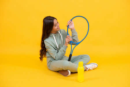 happy childhood. be hydrated. kid sit with racket and water bottle. child with tennis racquetの写真素材