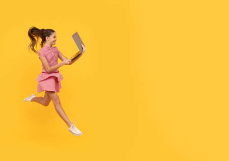 cheerful teen girl run with computer for study online, copy space, back to schoolの写真素材