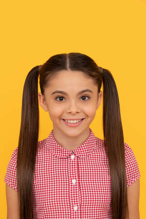 Smile lit up her face. Smiling child face. Happy girl portrait yellow backgroundの写真素材