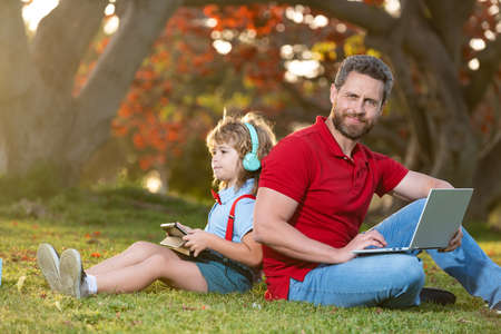 father and son use modern communication technology in park. family blog.