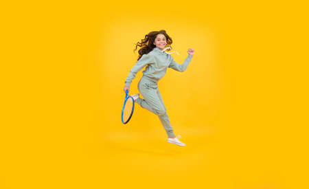 energetic child with tennis racquet. teen girl run to training. dedicated to fitnessの写真素材