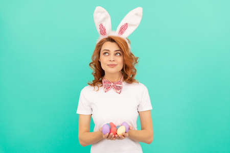 happy redhead girl in bunny rabbit ears with painted eggs, easter huntの写真素材