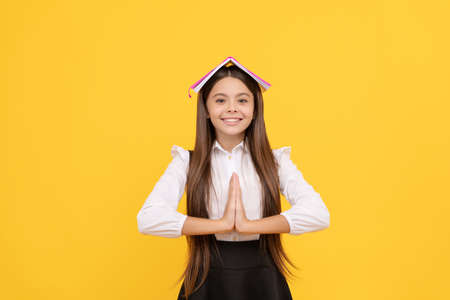 happy teen girl in school uniform with book on head meditating with hand gesture, keep calmの写真素材