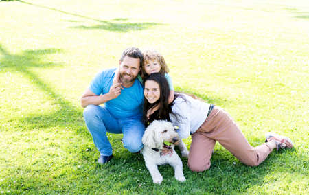 happy family portrait of mom dad and kid boy playing with pet in park on green grass, togethernessの写真素材