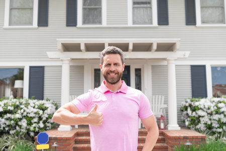 happy owner show thumb up. ownership. confident man outside new american home.の写真素材