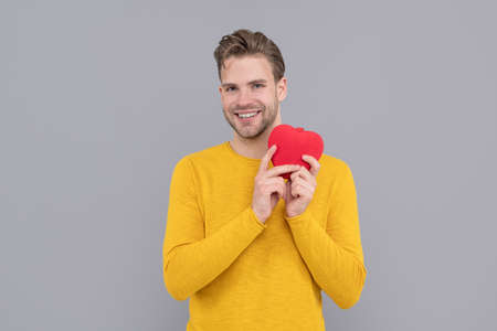 Happy young man smile holding Valentines heart grey background, love